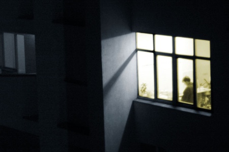 Person viewed through window, working late in office