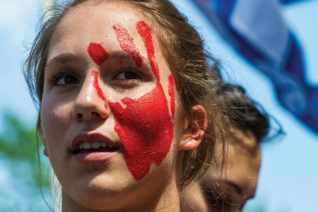 Woman with red hand print painted on face