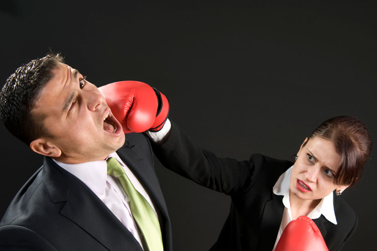 Boxing businesswoman punching man in face