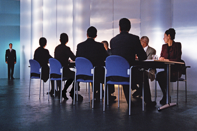 Businessman standing before table of executives