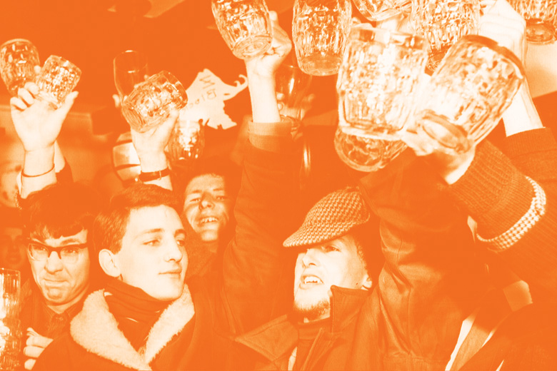 Crowd of men raising pint glasses in pub