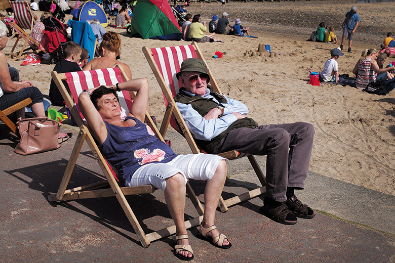 Elderly British couple in deckchairs at the seaside