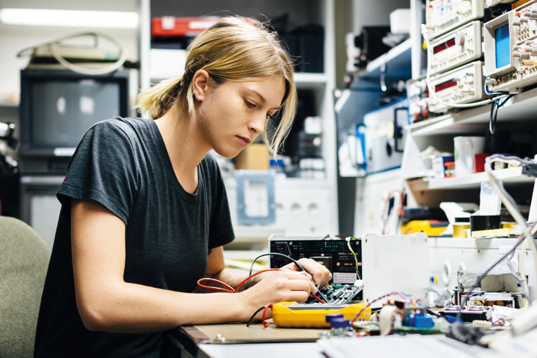 Female engineer measuring voltage on conductor board