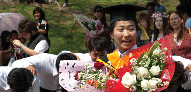 Thai female graduate holding bunches of flowers