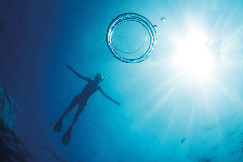 Scuba diver swimming in clear blue water