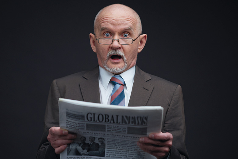 Shocked man reading newspaper