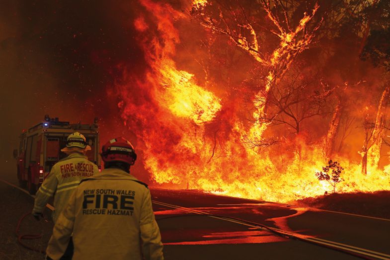 Fire and Rescue personnel run to move their truck as a bushfire burns near the town of Bilpin