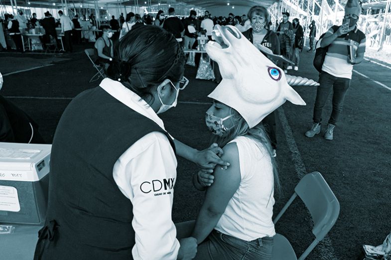 woman wearing unicorn hat gets vaccinated