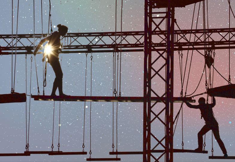 Silhouette of two people on climbing ropes.