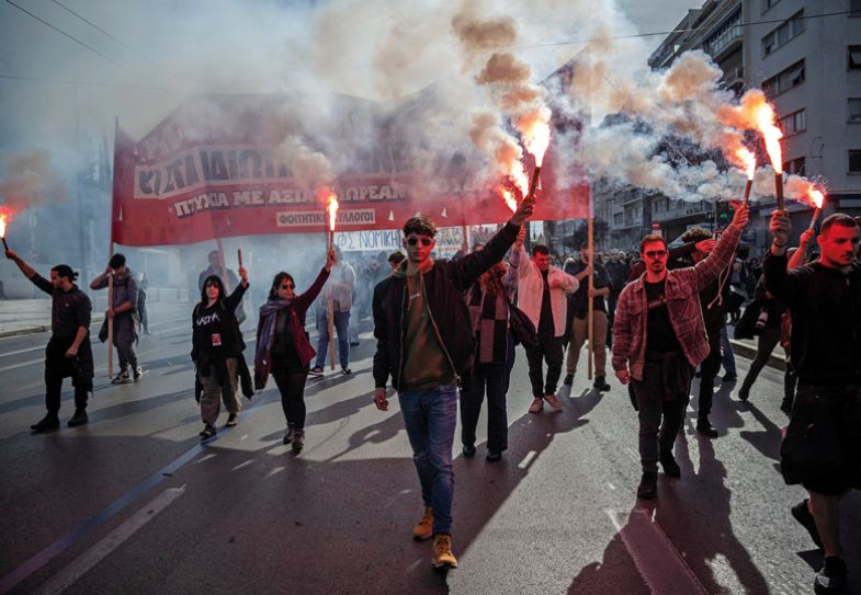 Students hold flares as they take part in a demonstration against the government's plans for private universities to illustrate Private universities law will stem Greek diaspora, minister says