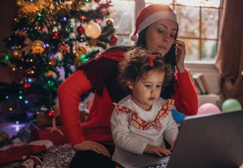 Mum with daughter on lap while working on laptop illustrating working from home