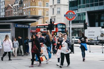 People walking outside a busy Aldgate East tube station, London