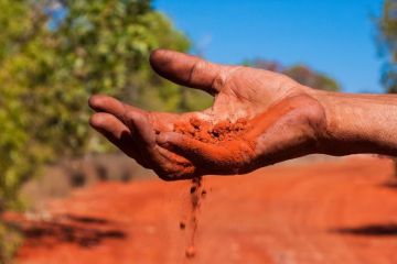 Red Australian earth slips through Indigenous Australian’s fingers