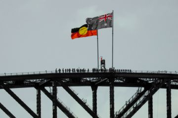 The Australian and Australian Aboriginal flags fly on the Sydney Harbour Bridge