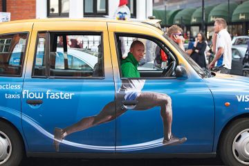 Taxi cab with advertisement on the side that adds body to driver's head, humorously