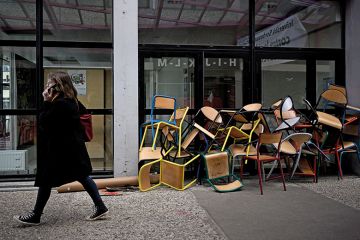 A student walks past a pile of chairs blocking a door of the Bordeaux Montaigne University, in Pessac