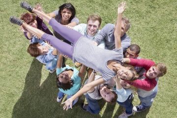 A group of people hold up a woman, symbolising collaboration