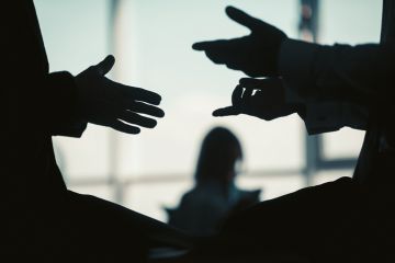 Two people in silhouette have a conversation