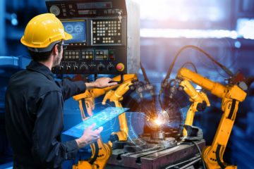 A man controls robot arms with an iPad, illustrating degree apprenticeships