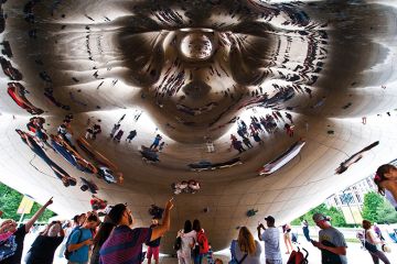 People reflected in shiny sculpture