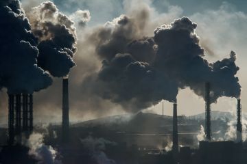 Black smoke rises from chimneys on industrial plant