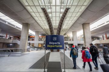 Picture of passengers with their suitcases passing near one of the displays of the departures hall of terminal 2 in charles de Gaulle Airport