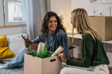 Two young women unpacking in a room