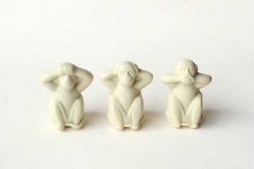 Three monkey statuettes in 'see no evil, hear no evil, speak no evil' poses