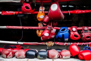 Boxing gloves hang off a boxing ring