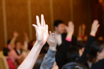 Students putting hands up in lecture theatre