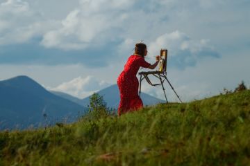 A woman paints on a mountain slope, illustrating practice research