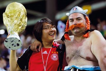 A South Korean supporter (L) holds a miniature replica of the World Cup trophy to illustrate Overseas drive ‘puts HE quality at risk’