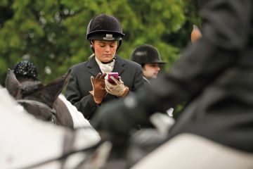 A woman on a horse uses a mobile phone