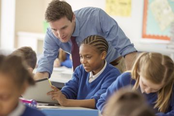 A schoolteacher helps his pupils