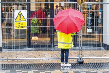 Someone with an umbrella stands by a barrier