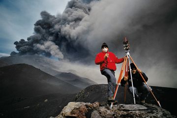 Geologists stand before an eruption on Mt. Etna in November 2002, and take readings