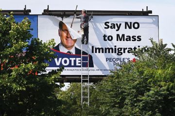 A worker removes a billboard featuring the portrait of People’s Party of Canada (PPC) leader Maxime Bernier to illustrate Canadian universities fear loss of consensus on global role