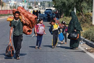 People carrying some of their belongings reach the central Gaza Strip to illustrate Gaza war drives scholars’ exodus