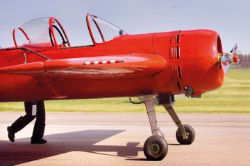 A bright red plane appears to have legs, as a pilot pushes his aircraft to illustrate UK funding council budgets set to drop