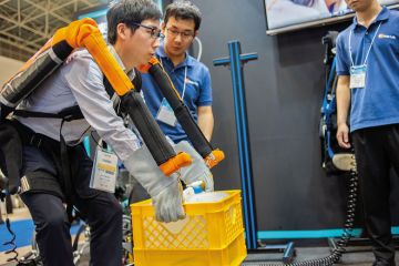 A visitor tries an exoskeleton robot suit during the Japan Robot Week exhibition in Tokyo to illustrate AI ‘could worsen burden of admin’ 