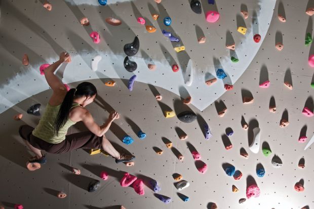 A woman scaling a climbing wall