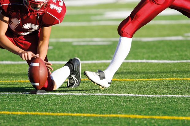 American football player preparing to kick ball