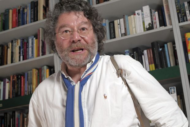 Author Craig Raine standing in front of bookcase