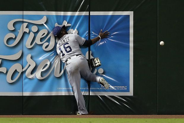 Baseball player running into wall trying to catch ball