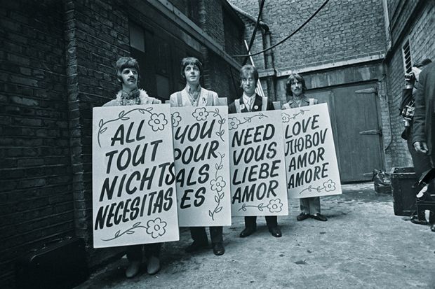 The Beatles hold sandwich boards with lyrics in different languages