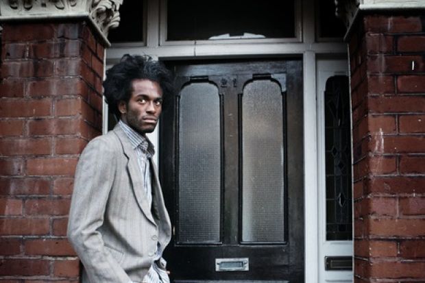 A black man waits in a doorway illustrating opinion article about equity in higher education