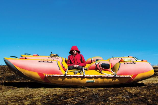 Boy sitting alone on boat in field