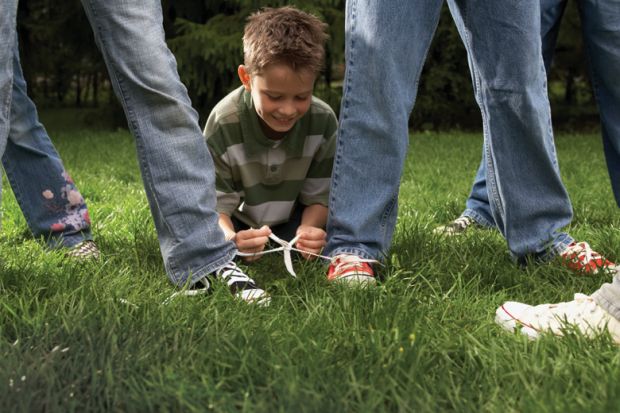 Boy ties two people's shoes laces together