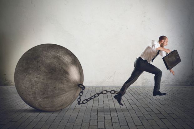 Businessman running with ball and chain on ankle