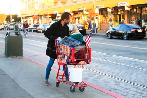 Homeless man pushing shopping cart full of belongings